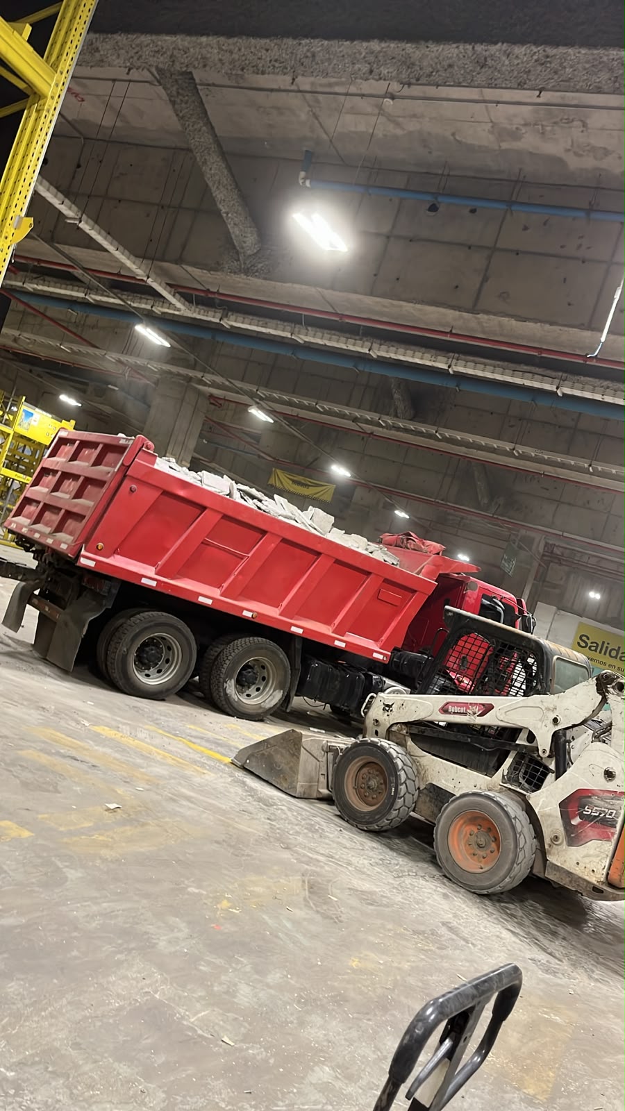 Camión tolva rojo y minicargador durante un retiro de escombros